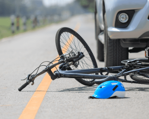 A bicycle in the road with a helmet under a car.