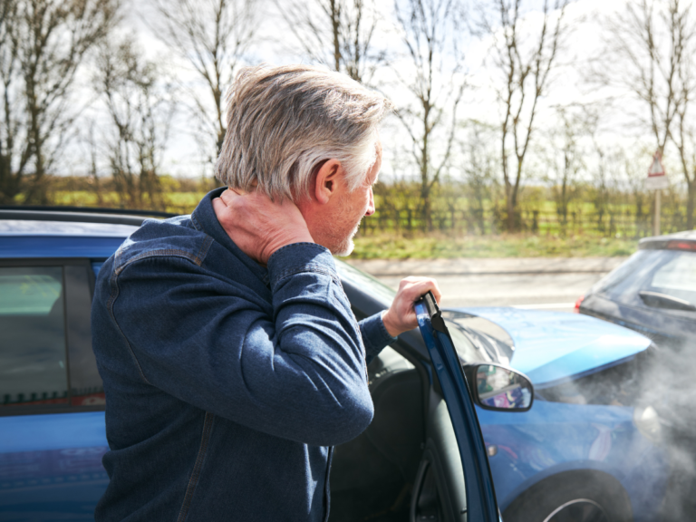 Man getting out of car holding his neck