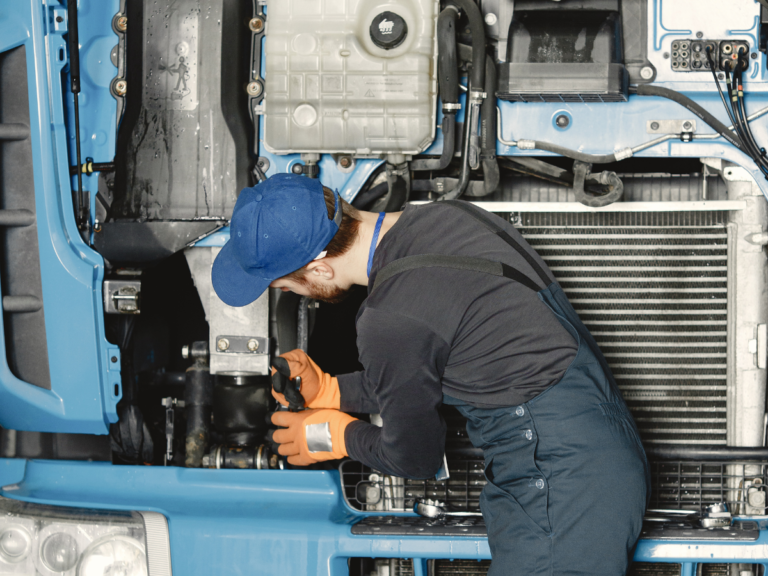 A man working under the hood of a semi truck.