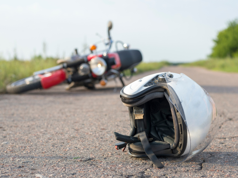 A motorcycle on the ground in the background and a silver helmet in the foreground.