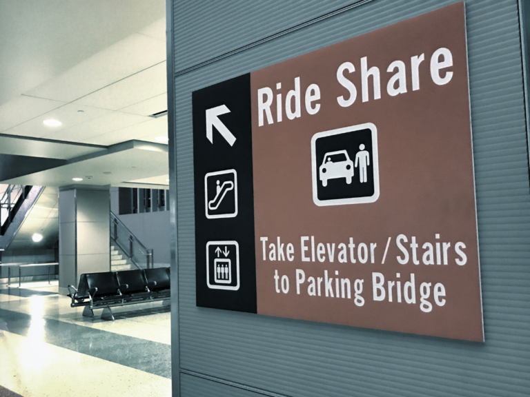 A sign with an arrow that points to a Rideshare Pickup area.